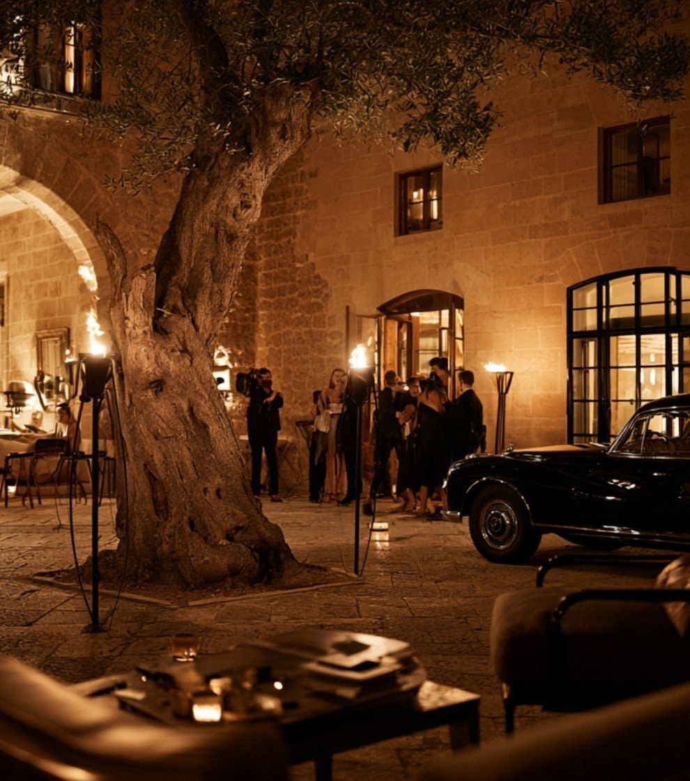 Torch-lit palacio courtyard with an olive tree and leather lounge chairs