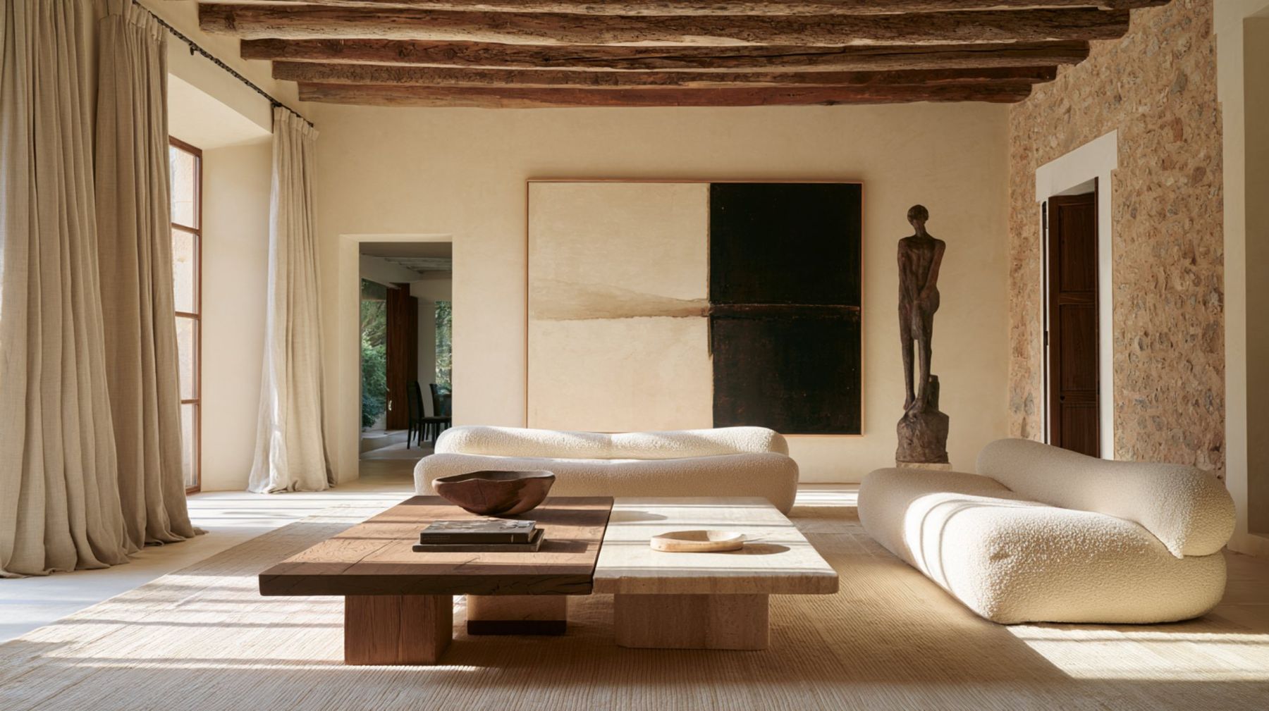 Great room of a stone finca with old beams and cream sofas