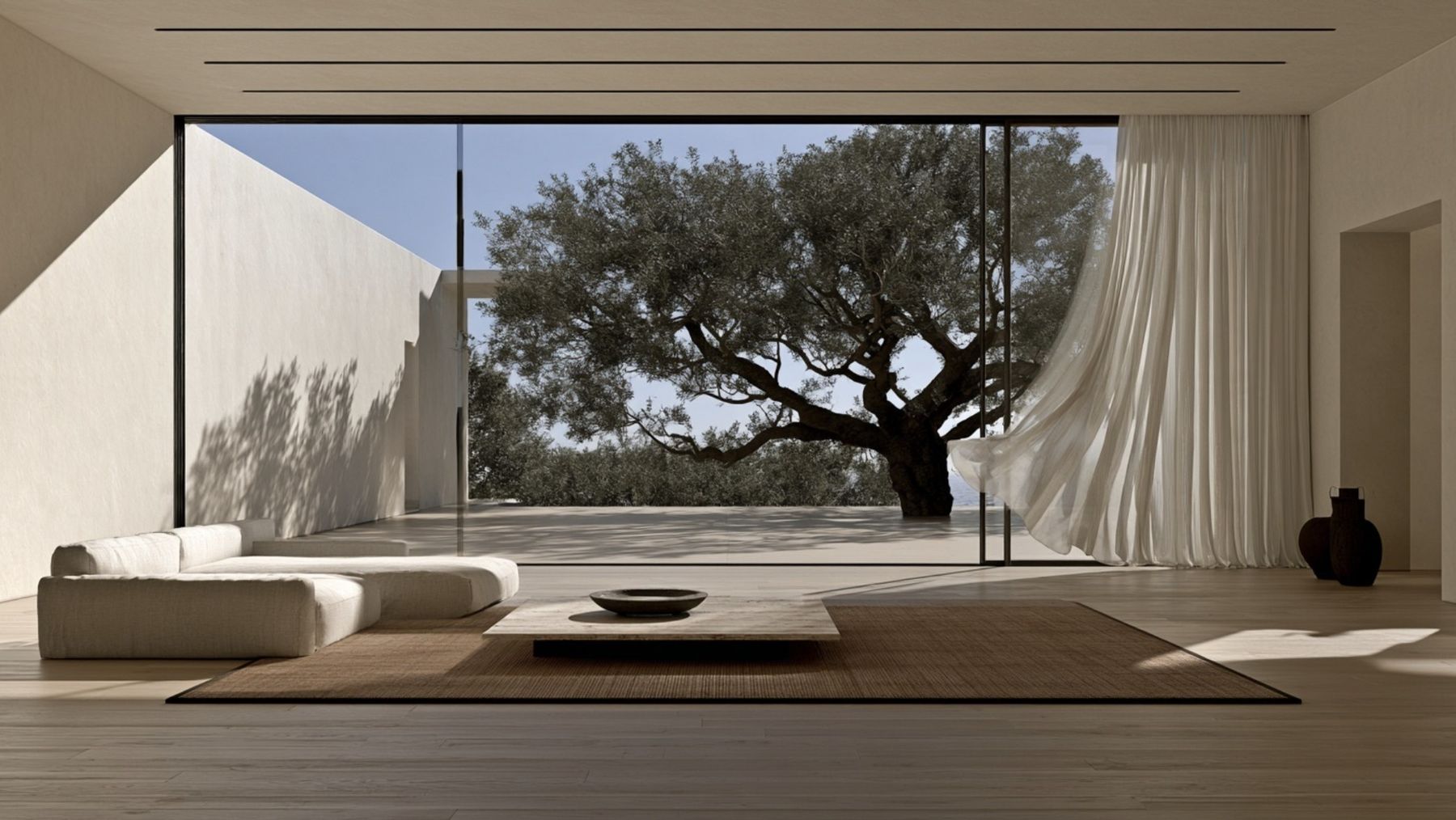 Calm living room with a low linen sofa, travertine table and a wall of glass onto an old olive tree